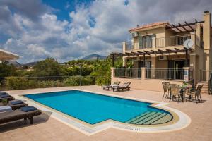 a swimming pool in front of a house at Aphrodite Blue in Trapezaki