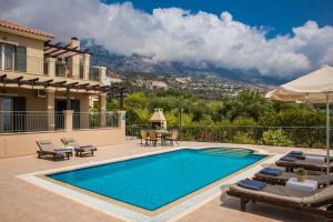 a swimming pool with chairs and a house at Aphrodite Blue in Trapezaki