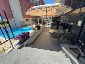 a patio with a table and an umbrella and a pool at Киво апарт Созопол in Sozopol