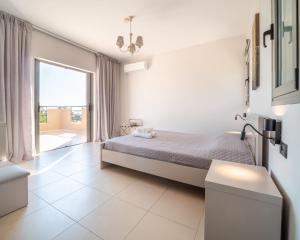 a white bedroom with a bed and a large window at Villa Joya by Villa Select in Skala +26 photos