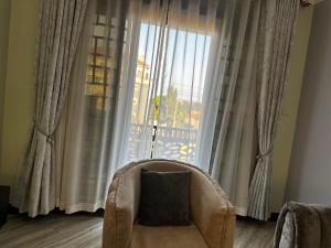 a chair with a pillow in front of a large window at El SALI APARTMENTS in Buwate