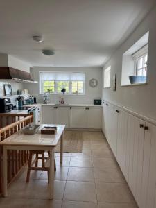 a kitchen with white cabinets and a table at Gorse cottage in Newton Abbot