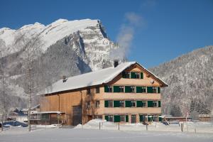 a building in front of a snow covered mountain at Jokelehof in Au im Bregenzerwald