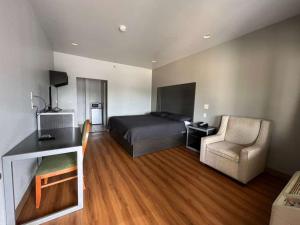 a bedroom with a bed and a couch and a chair at Century Inn in Dallas