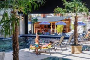 two children sitting on chairs by a swimming pool at Imperial Hotel&Spa - Baile Olanesti in Băile Olăneşti