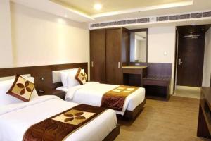 a hotel room with two beds and a desk at The Crystal Park in Kishangarh
