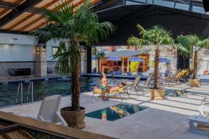 a pool with a palm tree and a child playing in it at Imperial Hotel&Spa - Baile Olanesti in Băile Olăneşti
