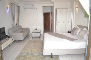 a bedroom with a bed and a couch and a chair at jPALACE in Bonamoussadi