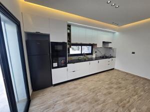 a kitchen with white cabinets and a black refrigerator at Dar Aalya in Djerba
