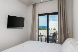 a hotel room with a bed and a window with a chair at Ostria Vento in Pollonia
