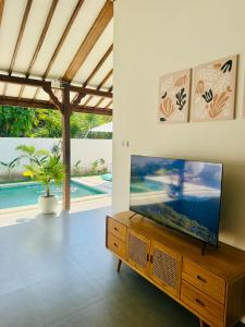 a living room with a flat screen tv on a wooden cabinet at VILLA Santay byAdiba in Gili Islands