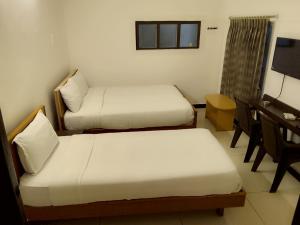 a room with two beds and a desk and a television at Arrow mansion in Kolli Hills