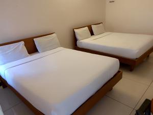 two beds with white sheets in a room at Arrow mansion in Kolli Hills