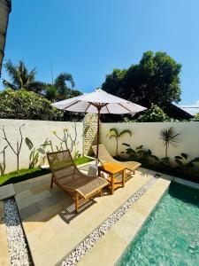 a patio with two chairs and an umbrella next to a pool at VILLA Santay byAdiba in Gili Islands