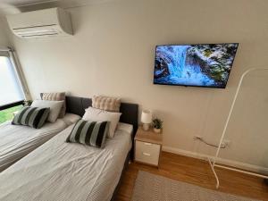 two beds in a room with a tv on the wall at Studio with private kitchenette and bathroom in Leumeah