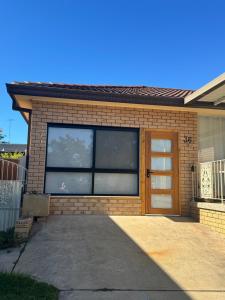 a brick house with a large window and a door at Studio with private kitchenette and bathroom in Leumeah