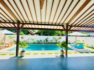 a pool with a wooden pergola and two plants at VILLA Santay byAdiba in Gili Islands