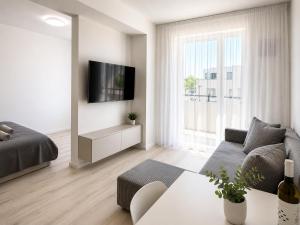 a white living room with a couch and a tv at Luxury White Residence in Trenčín