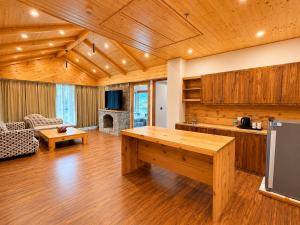 a large living room with a table and a kitchen at The himalayan chester in Manāli