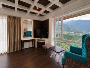 a living room with a blue chair and a large window at The himalayan chester in Manāli