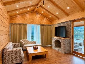 a living room with a fireplace and a tv at The himalayan chester in Manāli