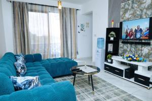 a living room with a blue couch and a tv at MtaaLiving-Bamburi in Mombasa