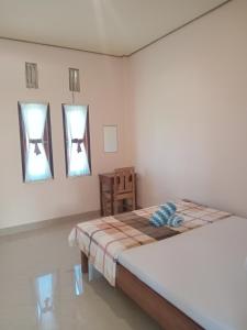 a white room with a bed and two windows at PENDIK Home Stay in Labuan Bajo