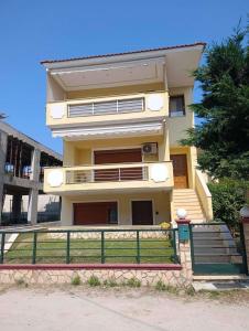 a yellow house with a green fence in front of it at Joanna's House in Nea Peramos