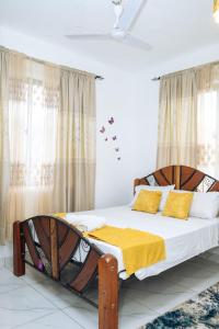 a bedroom with a large wooden bed with yellow pillows at MtaaLiving-Bamburi in Mombasa