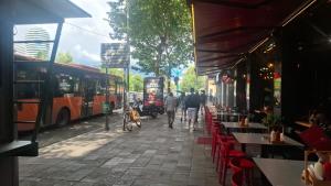 a group of people walking down a sidewalk next to buses at AA Tirana Center View in Tirana
