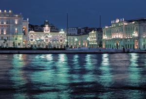 a city lit up at night with a body of water at Diaz 10 Suite in Trieste