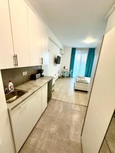 a kitchen with white cabinets and a living room at Mario Summerland Property in Mamaia