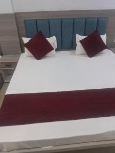 a large bed with two red pillows on it at HOTEL KRISHNAM Inn in Mathura