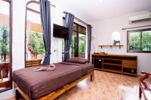 a bedroom with a bed and a tv and windows at Khao Sok Jungle Huts Resort in Khao Sok National Park