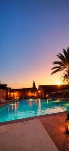 a large swimming pool with a palm tree and a building at Domaine JJ Marrakech in Marrakesh
