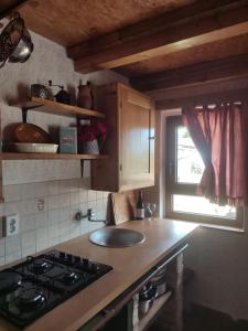 a kitchen with a stove and a sink and a window at Glas house Aljmaš in Aljmaš
