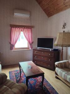 a living room with a tv and a couch and a table at Glas house Aljmaš in Aljmaš