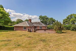 a small pink house on a grass field at Recently renovated Lodge Cottage, Quantocks in West Bagborough