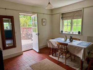 a dining room with two tables and a door to a yard at Recently renovated Lodge Cottage, Quantocks in West Bagborough +24 photos