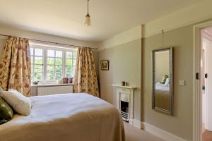 a bedroom with a bed with a mirror and a fireplace at Recently renovated Lodge Cottage, Quantocks in West Bagborough