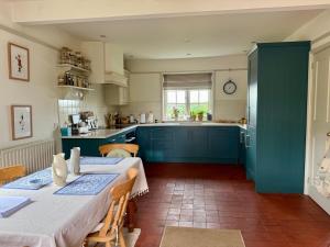 a kitchen with blue cabinets and a table and chairs at Recently renovated Lodge Cottage, Quantocks in West Bagborough