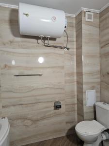 a bathroom with a toilet and a light on the wall at Византия in Sozopol +19 photos