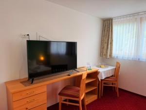 a large flat screen tv sitting on top of a wooden desk at Residenz Dunza Hotel Garni in Bürserberg