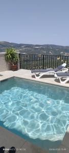 a swimming pool with chairs and a view of the ocean at Casa Rural Martemma in Zuheros