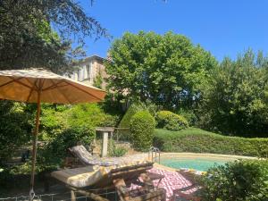 a pool with two chairs and an umbrella next to it at Bastide en Provence in Auriol
