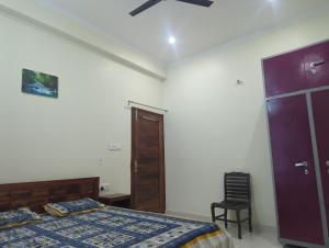a bedroom with a bed and a door and a chair at Panchsheel Villa Bhimtal in Bhīm Tāl