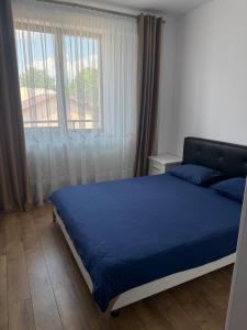 a bedroom with a blue bed and a large window at Eli house in Târgu Neamț