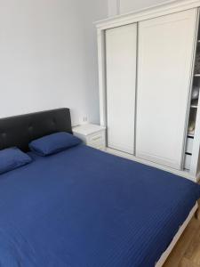 a bedroom with a blue bed and a large window at Eli house in Târgu Neamț