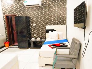 a bedroom with a bed and a chair at Shelton Royal Hotel in Multan