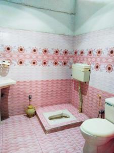 a pink bathroom with a toilet and flowers on the wall at Shelton Royal Hotel in Multan